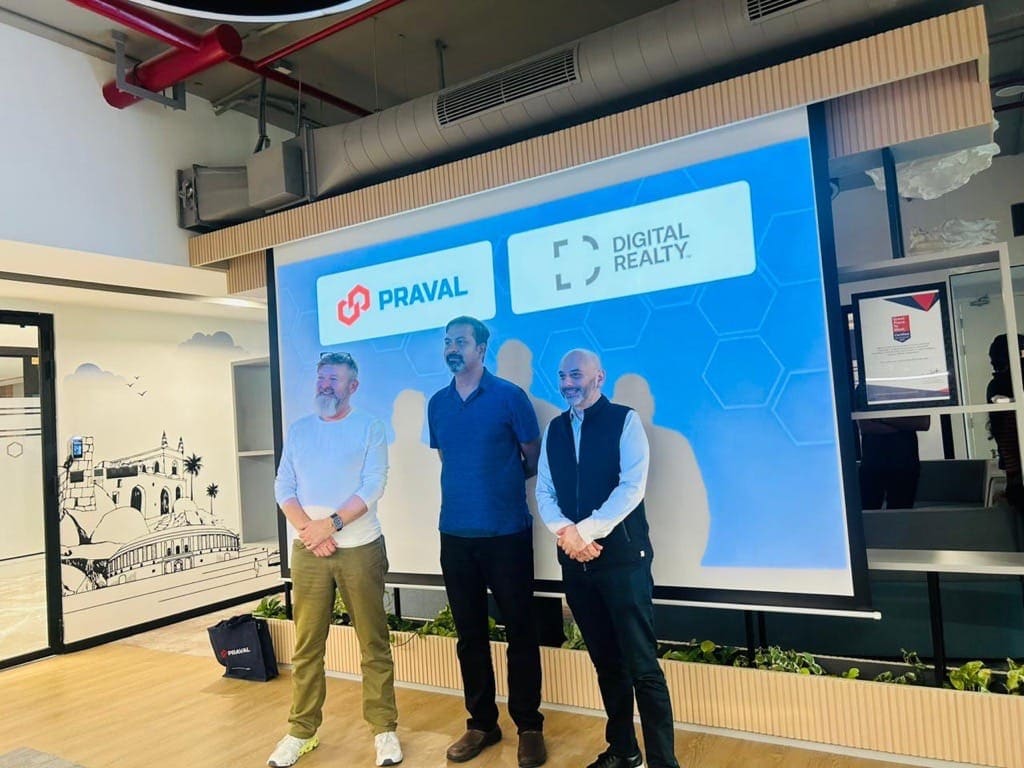 Three people in front of a screen showing the Praval and Digital Realty logos during a client visit